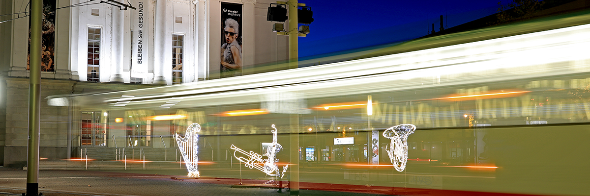 Lichterwelteninstallation vor dem Opernhaus mit einer bewegungsunscharfen Straßenbahn im Hintergrund