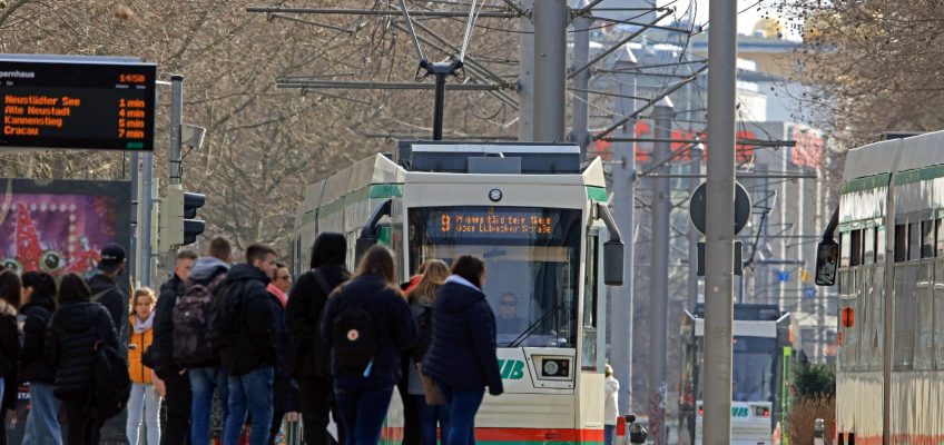 Menschen Warten an der Haltestelle Opernhaus während eine Straßenbahn vorfährt.
