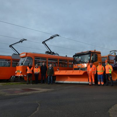 Team der Straßen- und Schienenwinterreinigung vor ihren Fahrzeugen.
