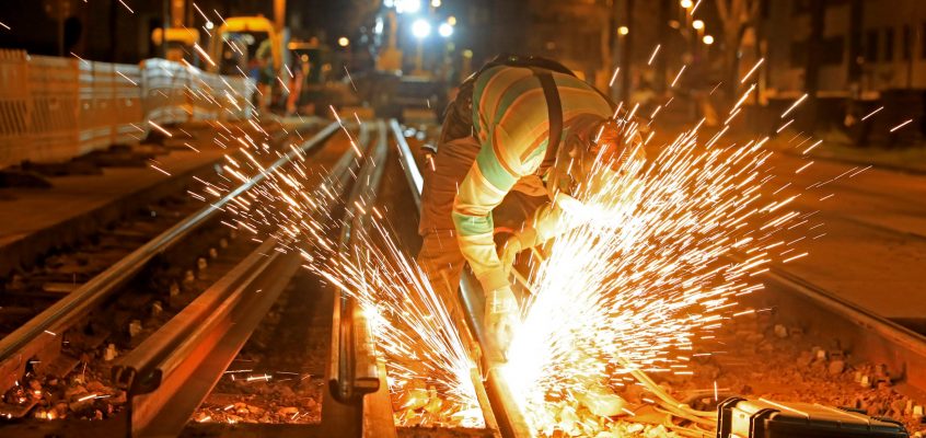 Schweißarbeiten an einer Gleisbaustelle bei Nacht. Es fliegen Funken.
