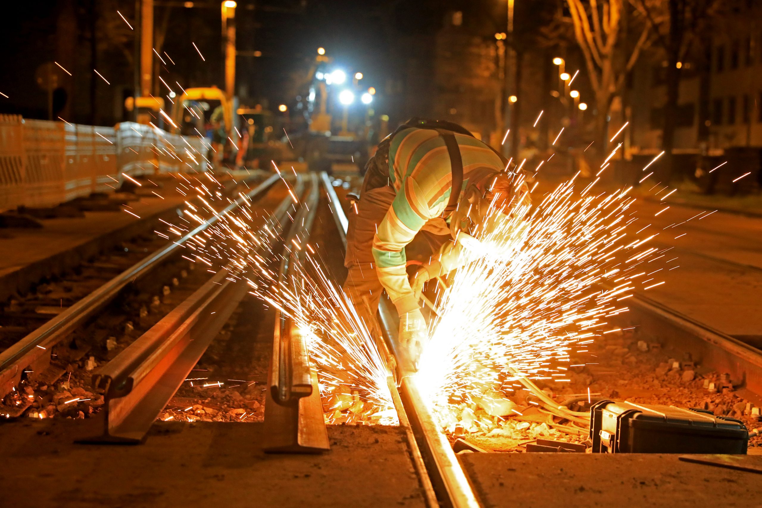 Schweißarbeiten an einer Gleisbaustelle bei Nacht. Es fliegen Funken.