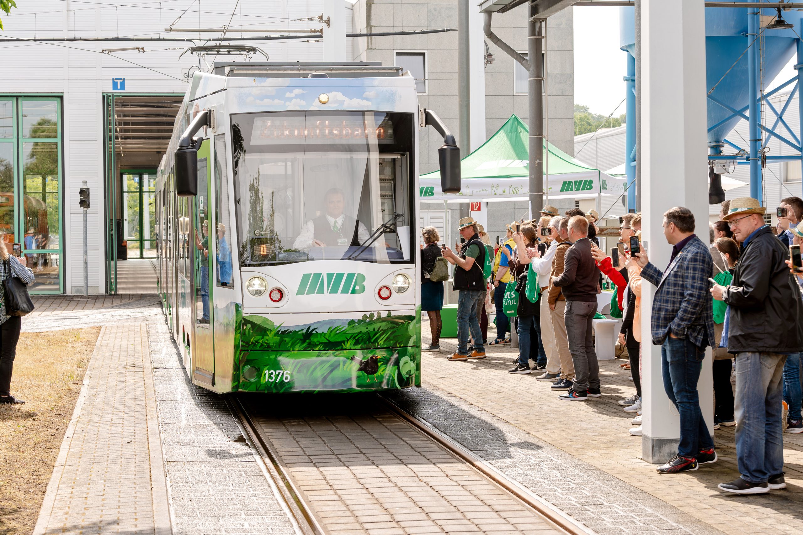 Die MVB-Zukunftsbahn fährt aus der Werkstatt. Publikum steht am Rand, applaudiert und filmt mit Handys.
