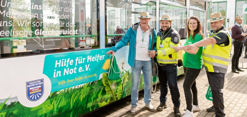 Vertreter des Hilfe für Helfer in Not e.V. vor der mit Vereinen bedruckten Zukunftsbahn mit dem gleichnamigen Schriftzug
