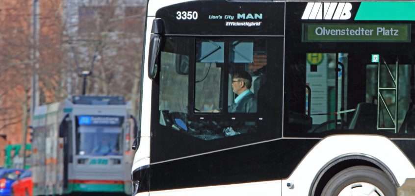 Bus im Profil und Straßenbahn im Hintergrund im Stadtverkehr.