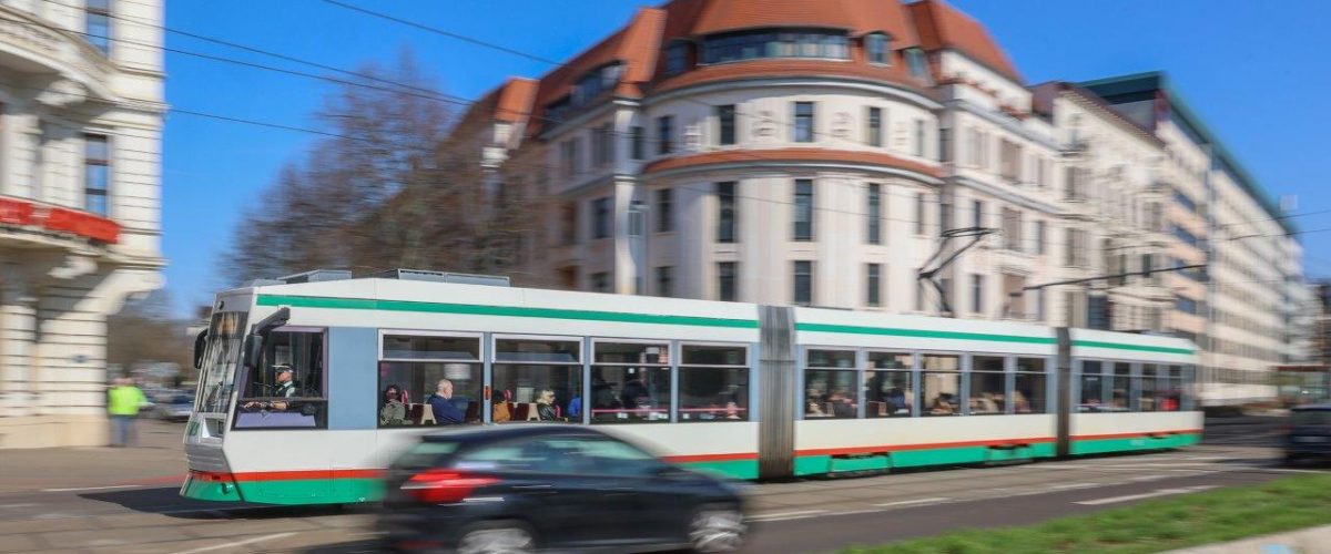 Bewegungsunscharfe Aufnahme einer Straßenbahn im Straßenverkehr.