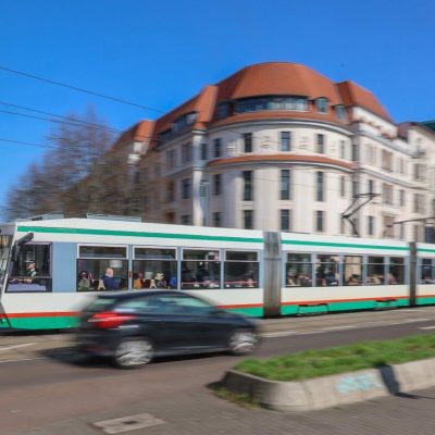 Bewegungsunscharfe Aufnahme einer Straßenbahn im Straßenverkehr.
