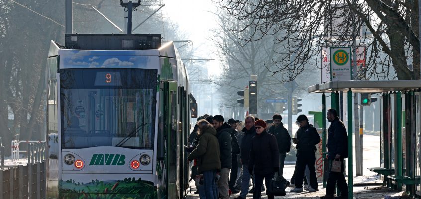 Straßenbahn der Linie 9 an der Haltestelle Neustädter Platz. Warm angezogene Passagiere steigen ein und aus.
