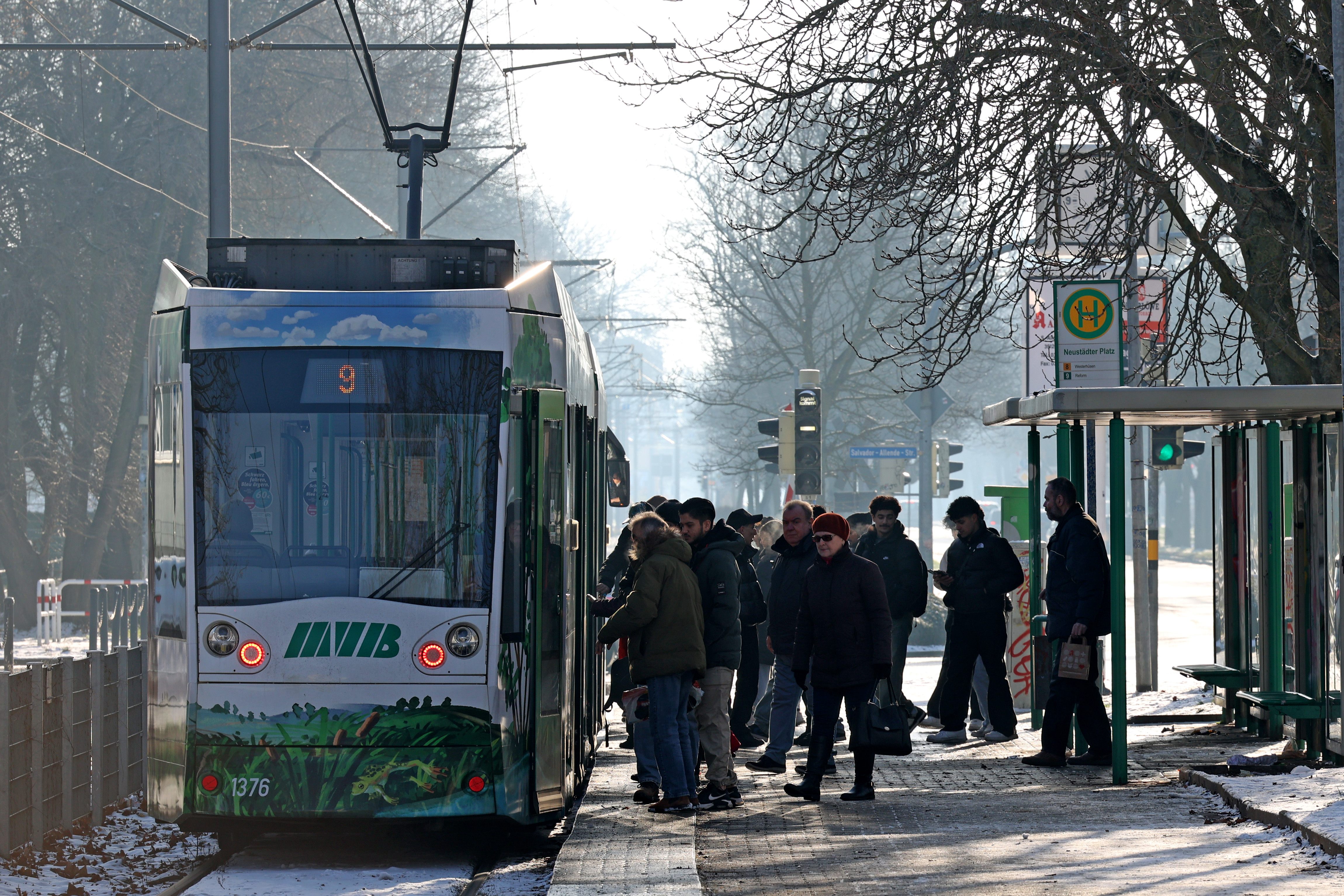 Straßenbahn der Linie 9 an der Haltestelle Neustädter Platz. Warm angezogene Passagiere steigen ein und aus.