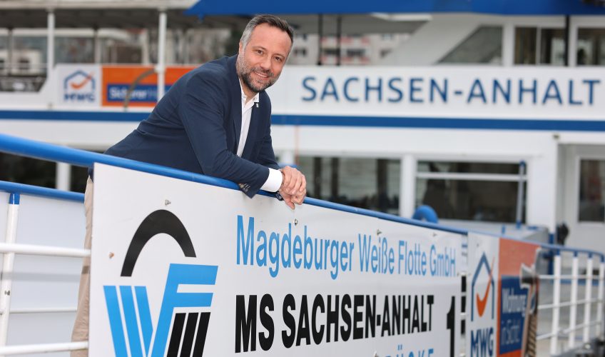 Hardy Puls, Geschäftsführer der Weißen Flotte auf einer Rampe mit dem Logo der Weißen Flotte, in die Kamera lächelnd
