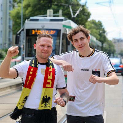 Zwei MVB Straßenbahnfahrer mit Deutschland Trikots vor einer Straßenbahn. Die Fahrer dürfen zur Heim Europameisterschaft das Trikot und nicht die Uniform tragen