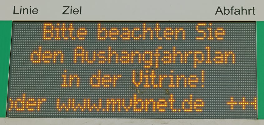 Nahaufnahme der elektronischen Fahrgastinformation, die darauf hinweist die Aushangsfahrpläne in der Vitrine zu beachten.