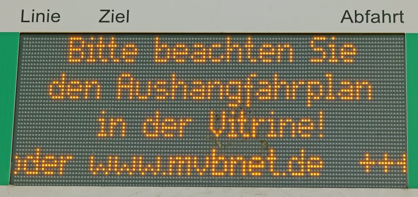 Nahaufnahme der elektronischen Fahrgastinformation, die darauf hinweist die Aushangsfahrpläne in der Vitrine zu beachten.