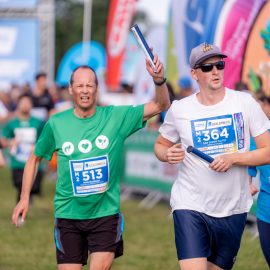 Läufer beim Firmenstaffellauf mit Staffelstab im Elbauenpark