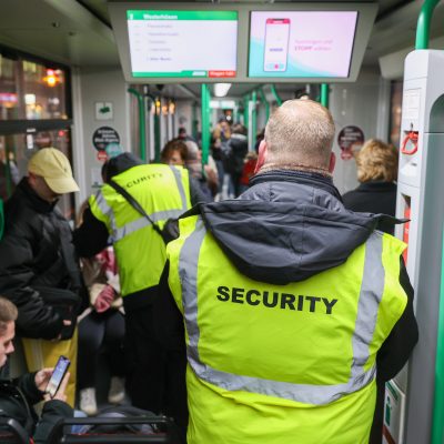 Sicherheitsmitarbeiten kontrollieren die Fahrscheine in einer Straßenbahn.