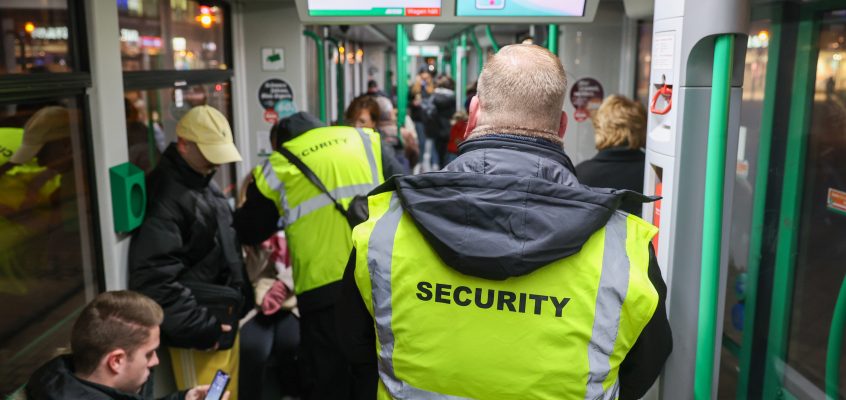 Sicherheitsmitarbeiten kontrollieren die Fahrscheine in einer Straßenbahn.