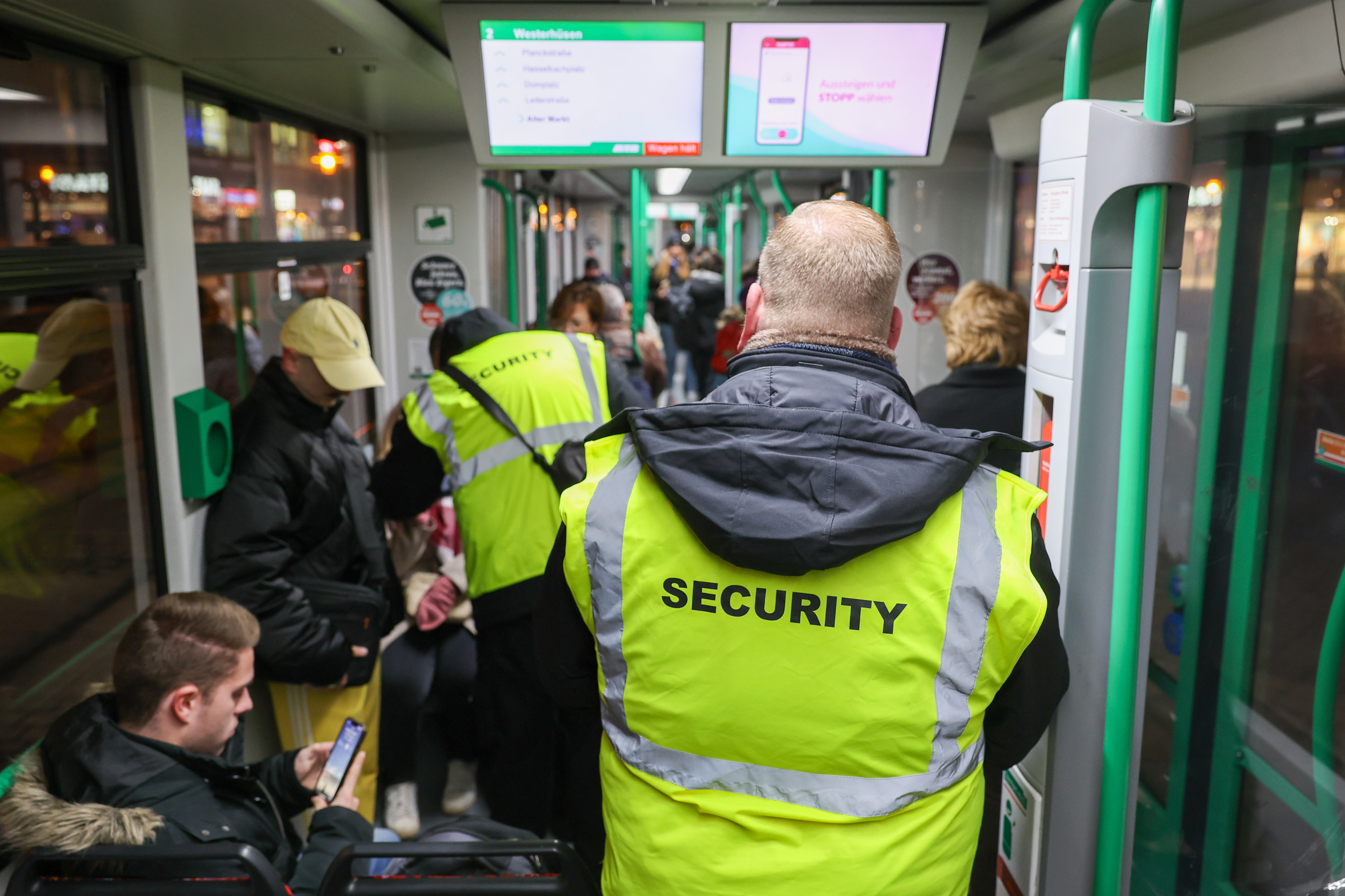 Sicherheitsmitarbeiten kontrollieren die Fahrscheine in einer Straßenbahn.