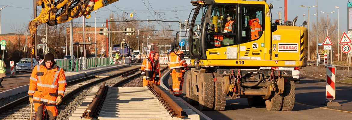Gleisbagger und Bauarbeiter arbeiten an neuem Gleisbett mit neuen schienensteilen an der MVB Strabag Baustelle am August Bebel Damm.
