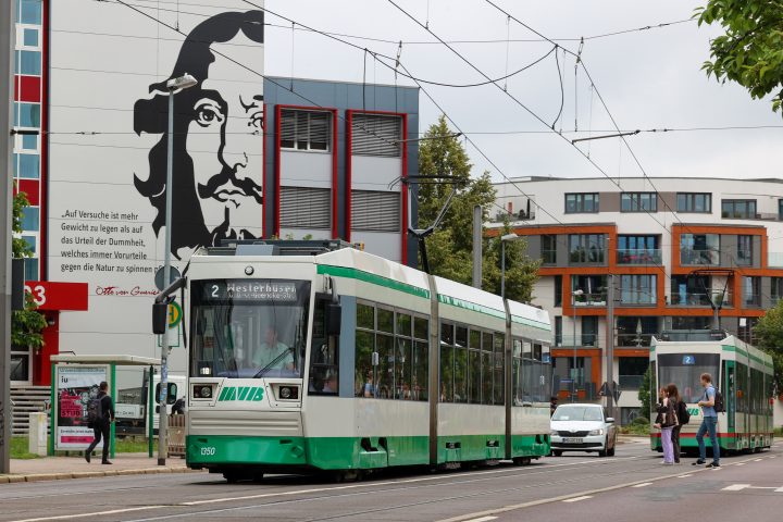 Straßenbahnen der Linie 2 an der Haltestelle Universitätsbibliothek. Menschen queren die Straße.
