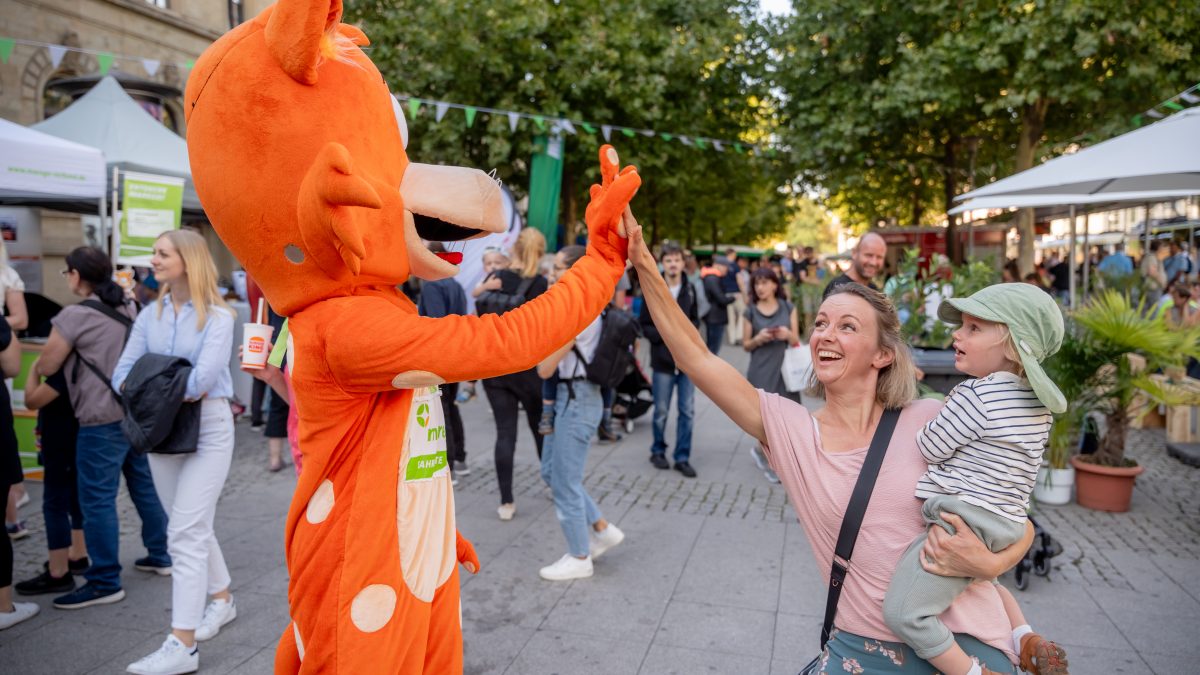 Fahrkarter-Maskottchen klatscht mit einer Mutter ab