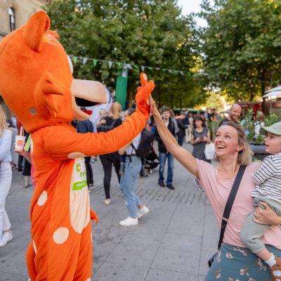 Fahrkarter-Maskottchen klatscht mit einer Mutter ab