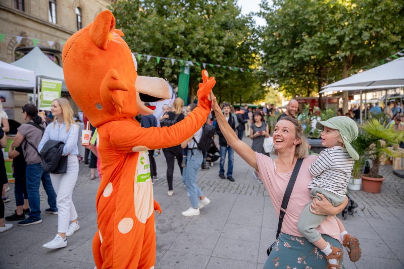 Fahrkarter-Maskottchen klatscht mit einer Mutter ab