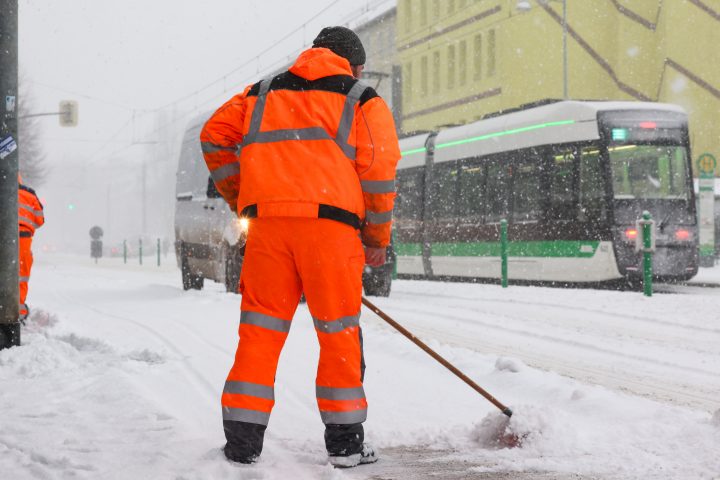 Mitarbeitende der MVB räumen die Straßen um die Haltestellen während des starken Schneefalls durch das Sturmtief Elli. Im Hintergrund ist die Flexity zu sehen.