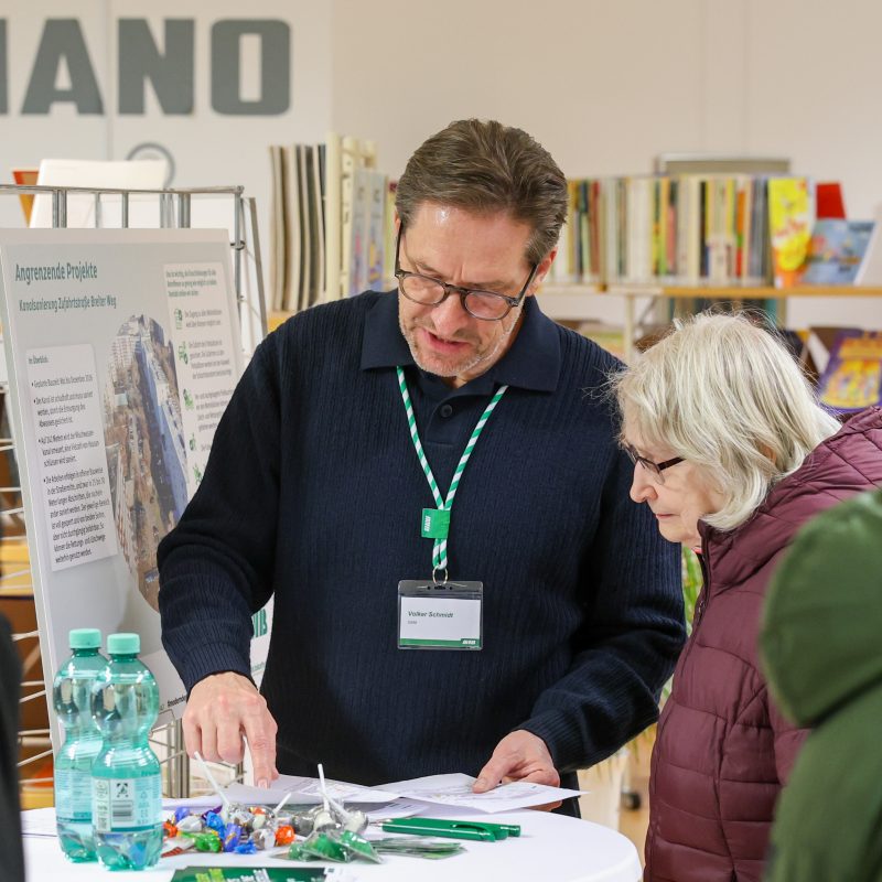 SWM Planer im Gespräch mit einer Bürgerin mit Blick auf die Pläne der Abwasserarbeiten der SWM am Alten Markt.
