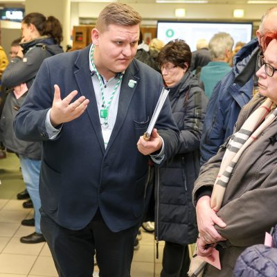 Ein Mitarbeiter der MVB im Gespräch mit Bürgern an einer Infowand.