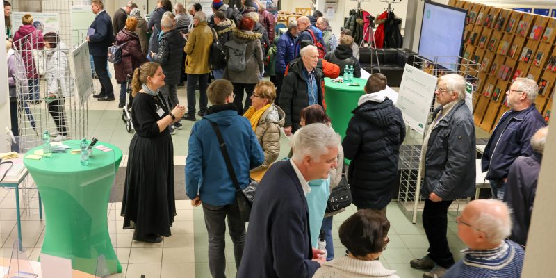 Menschen in der Lobby der Stadtbibliothek. Planer sprechen mit Bürgerinnen und Bürgern.