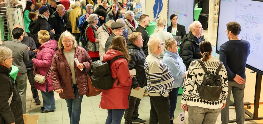 Infomarkt der MVB. Meschen stehen an den Infotafeln. MVB Planer erklären in der Stadtbibliothek das Bauprojekt und die Ausgelegten Pläne.