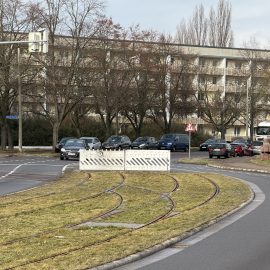 Blick in die Kritzmannstraße mit Straßenbahngleisen in der Straßenmitte. Am Bauende befindet sich eine Absperrung.