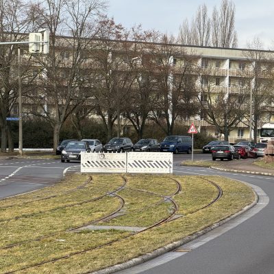 Blick in die Kritzmannstraße mit Straßenbahngleisen in der Straßenmitte. Am Bauende befindet sich eine Absperrung.