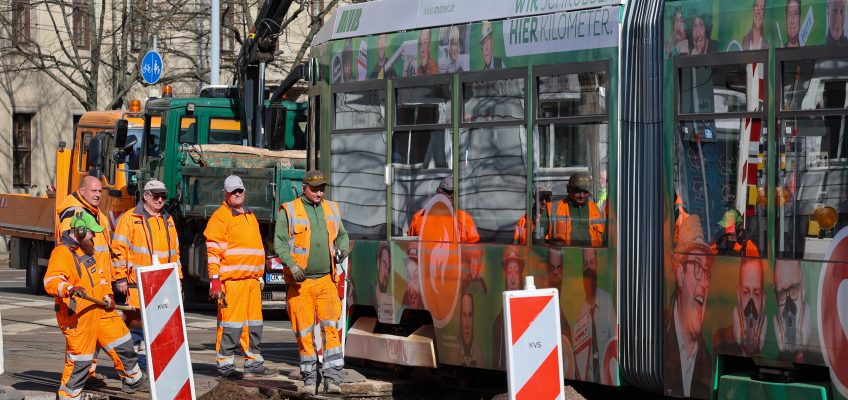 Gleisbaustelle auf der Leipziger Straße / Ecke Halberstädter Straße. Straßenbahn fährt an Bauarbeitern vorbei.