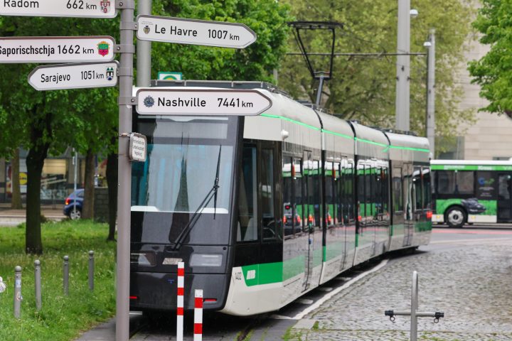 Die Flexity steht in der Hartstraße, ein Schild, auf dem die Partnerstädte der Stadt Magdeburg mit ihrer Entfernung abgebildet sind, steht im Verdergrund.