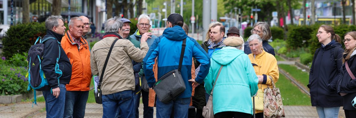 Teilnehmende eines Stadtrundgangs informieren sich am Breiten Weg über die Geschichte und Entwicklung des Nordabschnitts der Magdeburger Innenstadt.