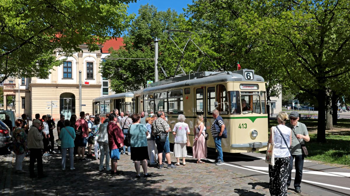 Historischer Gotha-Zug in der Hartstraße neben dem Rathaus. Viele Fahrgäste freuen sich davor auf die Abfahrt.