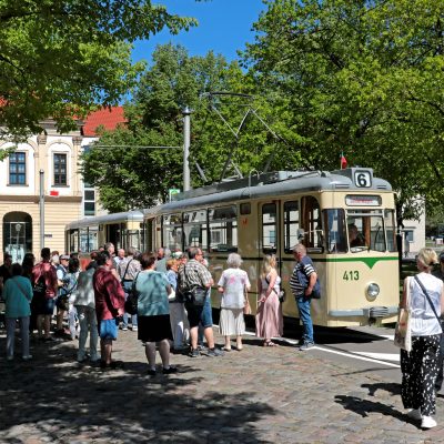 Historischer Gotha-Zug in der Hartstraße neben dem Rathaus. Viele Fahrgäste freuen sich davor auf die Abfahrt.