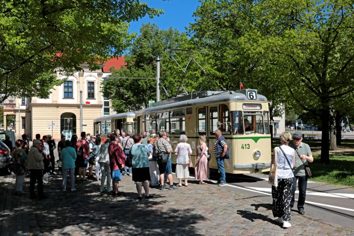 Historischer Gotha-Zug in der Hartstraße neben dem Rathaus. Viele Fahrgäste freuen sich davor auf die Abfahrt.